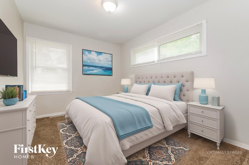 A bedroom with a bed, nightstands, and a painting on the wall.