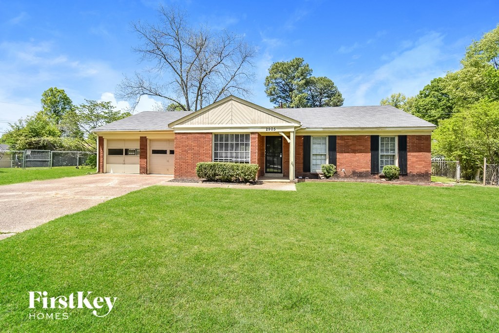A brick house with a green lawn in front.