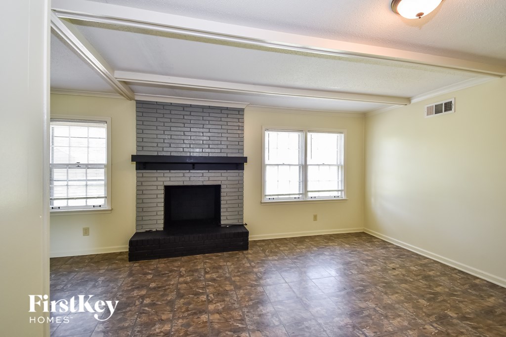 A room with a fireplace and two windows.