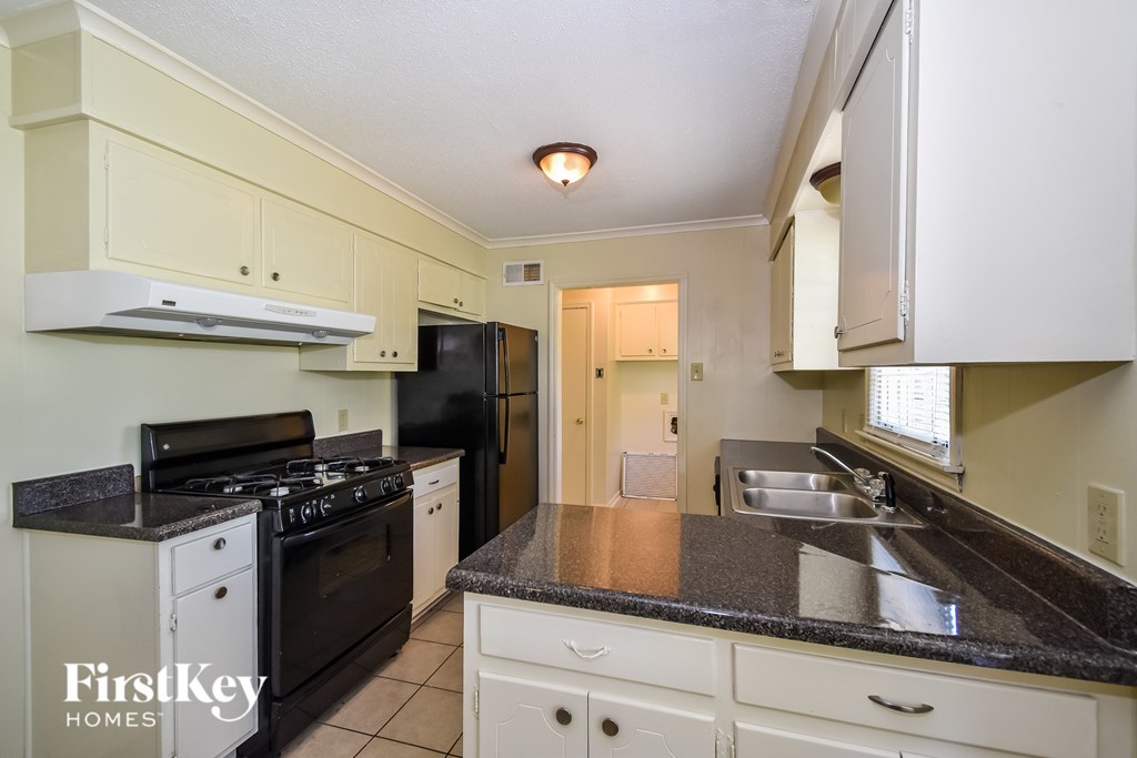 A kitchen with a black stove top oven and a black refrigerator.