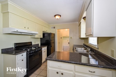A kitchen with a black stove top oven and a black refrigerator.