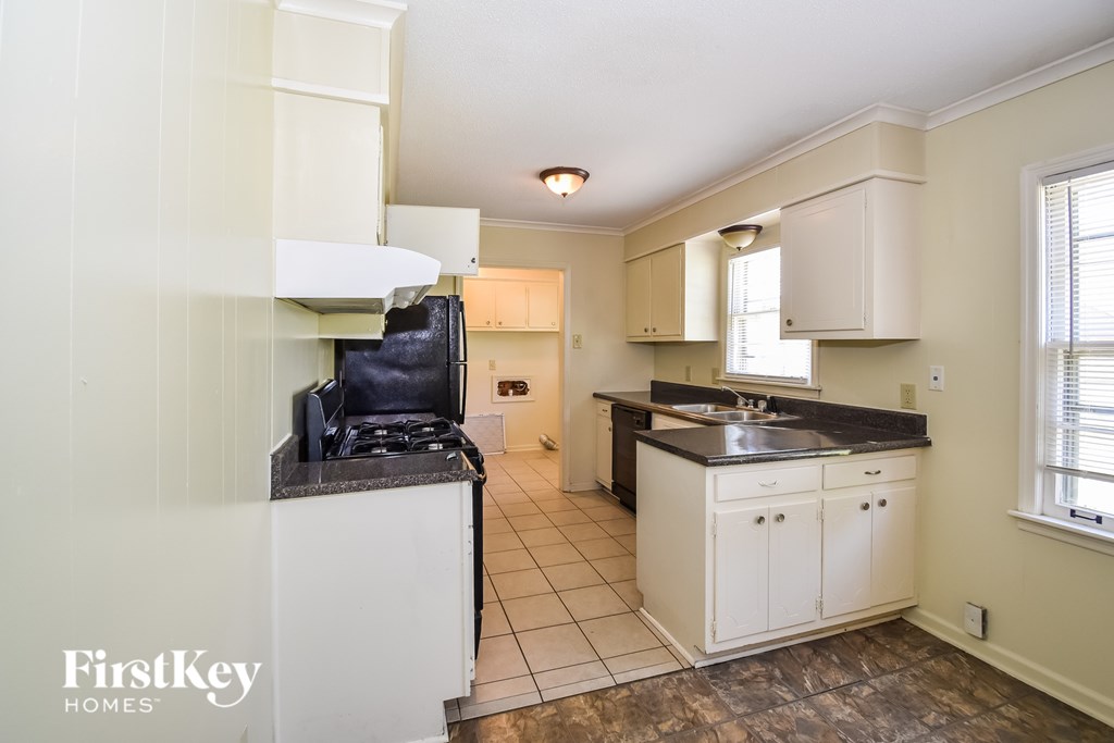 A kitchen with a black stove top oven and white cabinets.