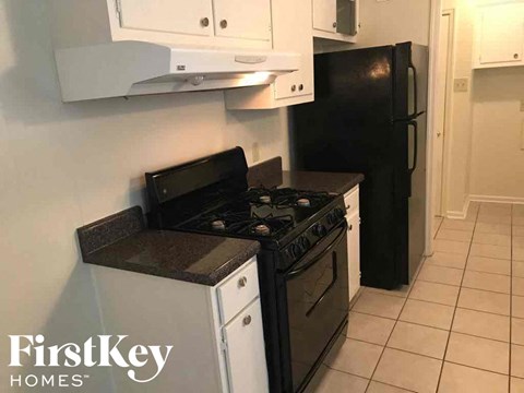 A black stove and refrigerator in a kitchen with white cabinets.