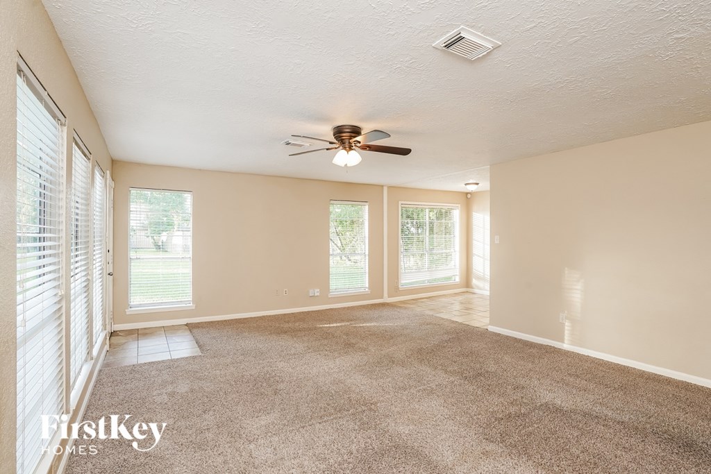 A room with a carpet floor and a ceiling fan.