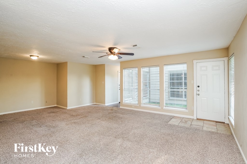 A spacious room with a ceiling fan and sliding glass doors.