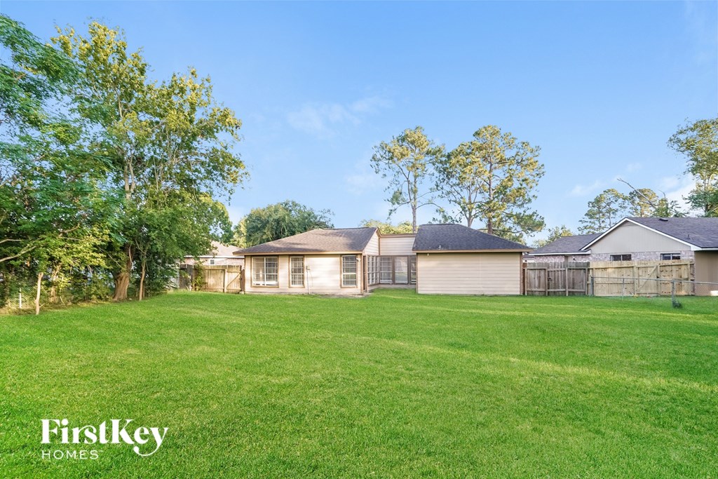 A grassy field with trees and a house in the background with the words "FirstKey Homes" on the bottom left.