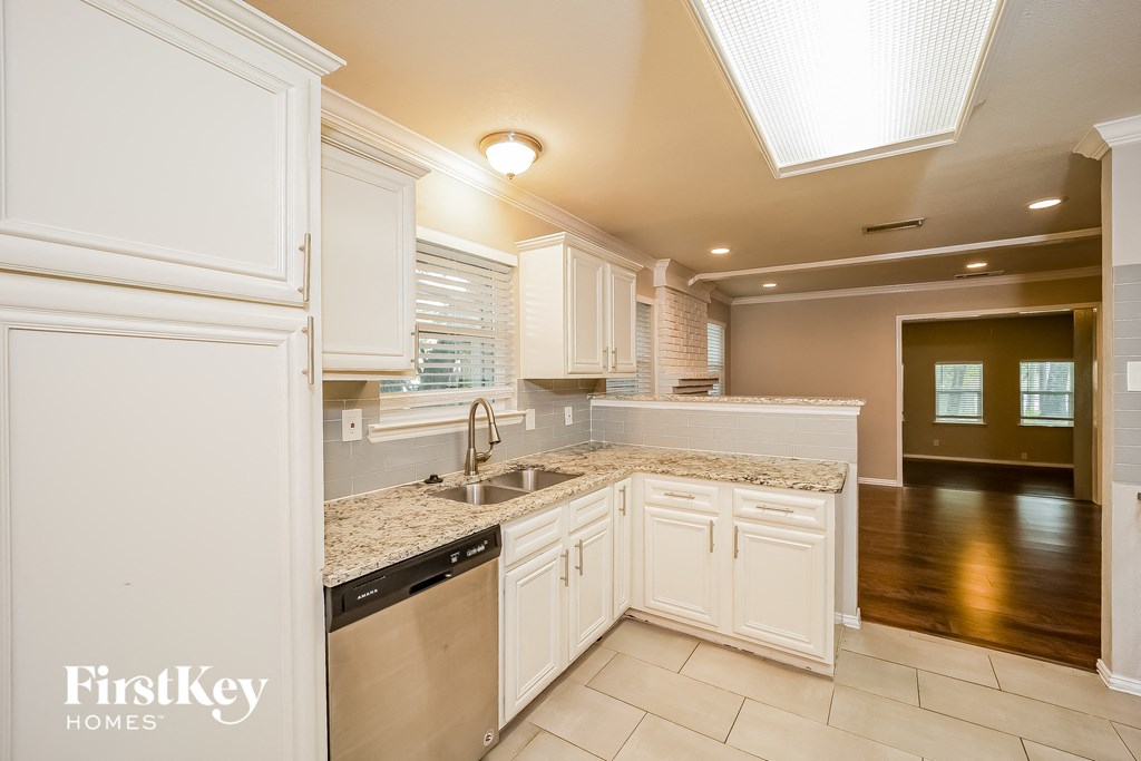 A kitchen with white cabinets and a granite countertop.