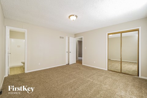 a master bedroom with carpet and mirrored closet doors
