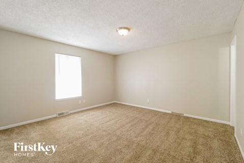 the spacious living room with carpeting and a window