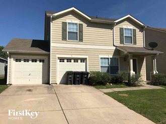 a tan house with two garage doors and a driveway