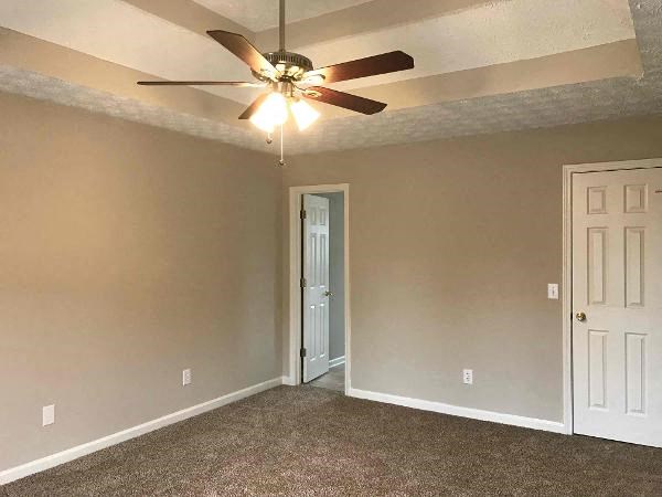 an empty living room with a ceiling fan and a door