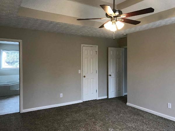 an empty living room with a ceiling fan and a door