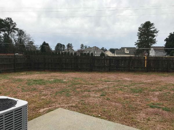 a backyard with a wooden fence and a grass field