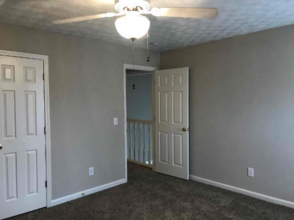 an empty room with a ceiling fan and a door