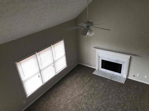 an empty living room with a fireplace and a ceiling fan