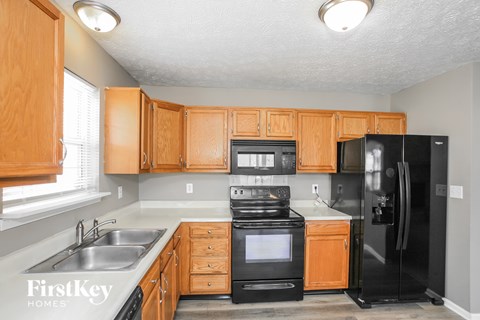 A kitchen with wooden cabinets and a black refrigerator.