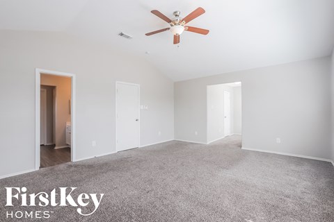 a living room with carpet and a ceiling fan