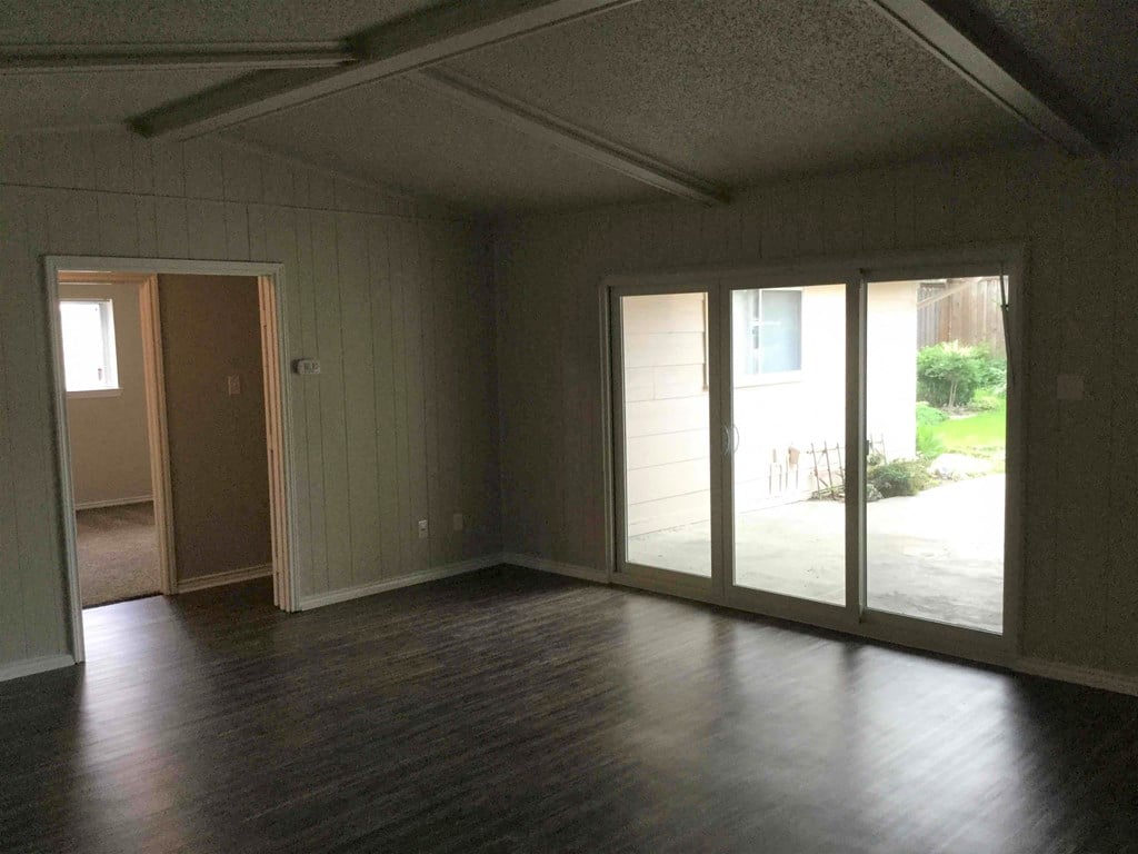 A room with a sliding glass door and hardwood floors.