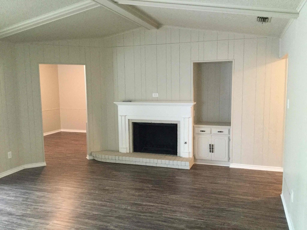 A living room with a fireplace and wood flooring.