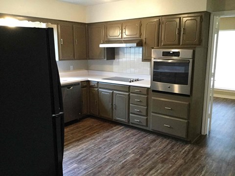 A kitchen with a black refrigerator and stainless steel appliances.