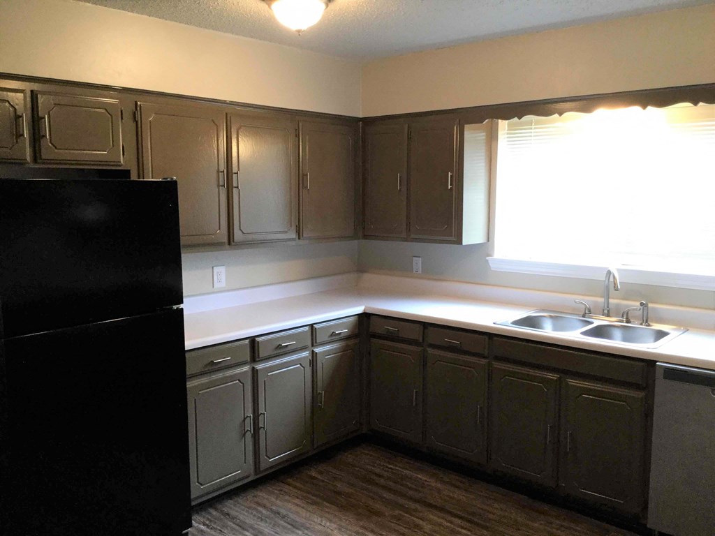 A kitchen with a black refrigerator and wooden cabinets.