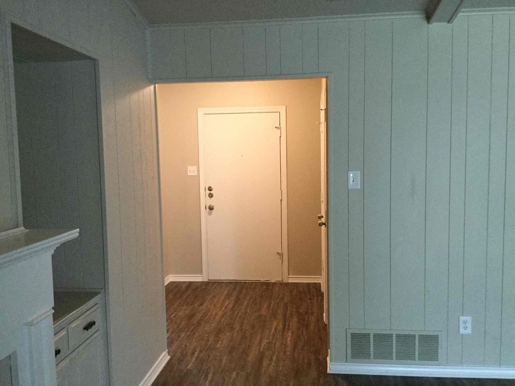 A room with a white door and a wooden floor.