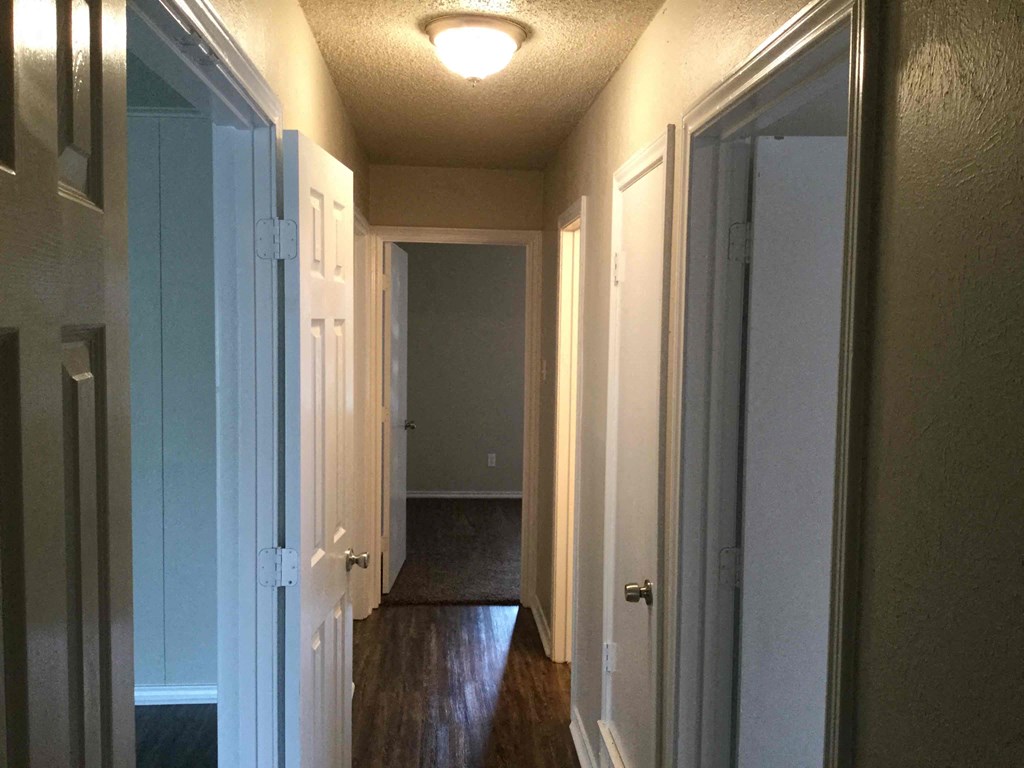 A long hallway with white doors and a light on the ceiling.