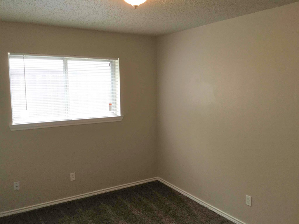 A room with a window and a carpeted floor.