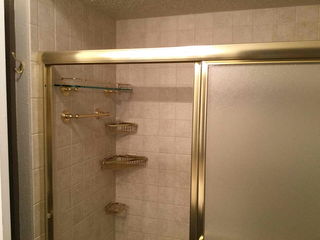 A bathroom with a shower curtain rod and shelves.