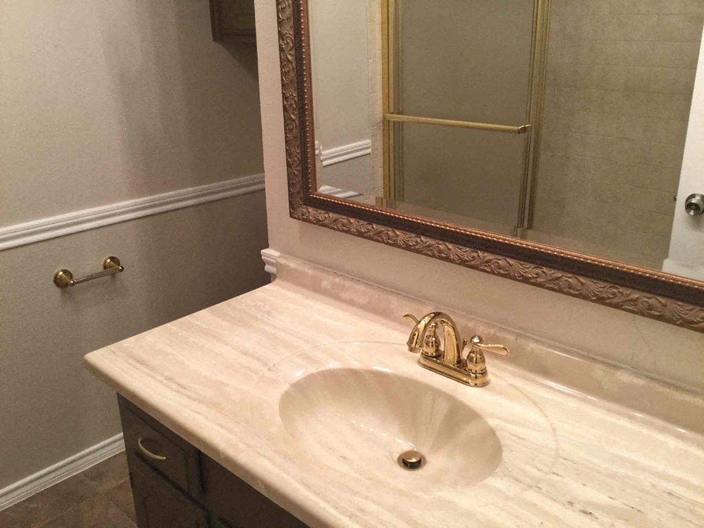 A bathroom sink with a gold faucet and a mirror above it.