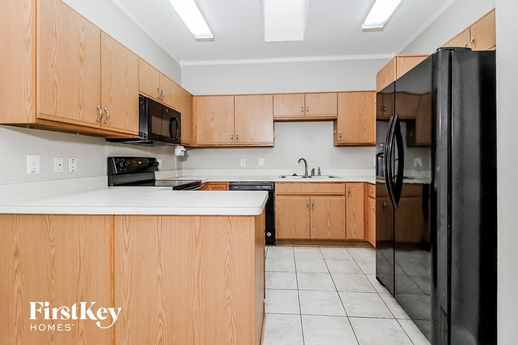 A kitchen with wooden cabinets and a black refrigerator.