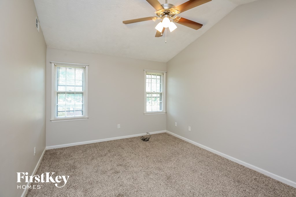 an empty room with a ceiling fan and two windows