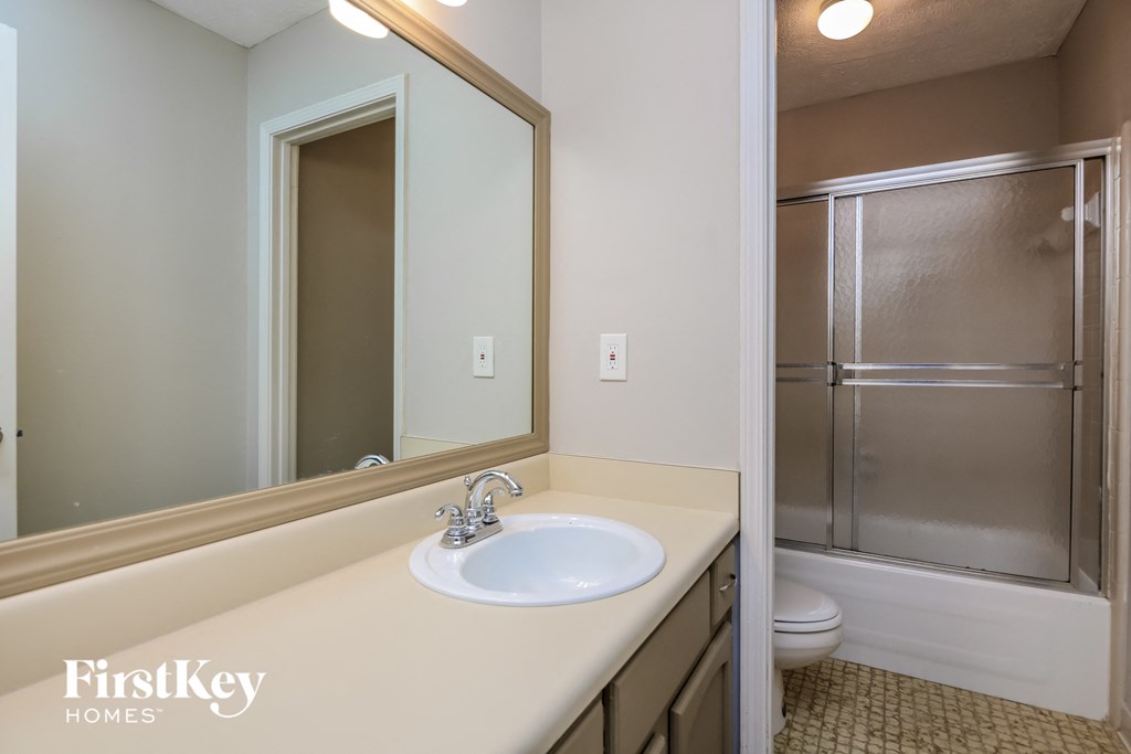 a bathroom with a sink and a shower and a mirror