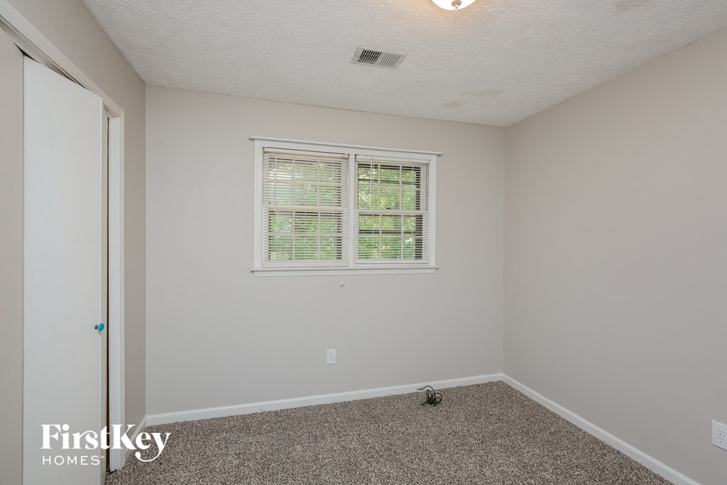 the living room of an empty house with carpet and a window