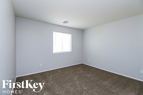 the living room of a small white house with carpet and a window