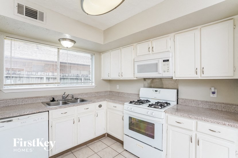 A kitchen with white cabinets and appliances.