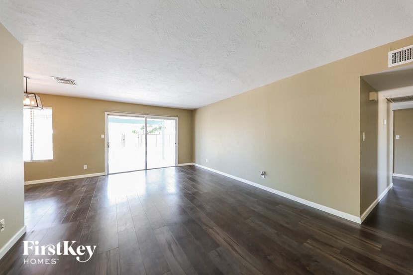 an empty living room with wood floors and a door to a patio