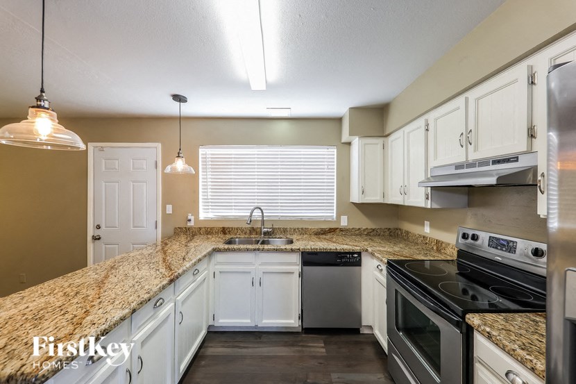 a kitchen with white cabinets and granite counter tops