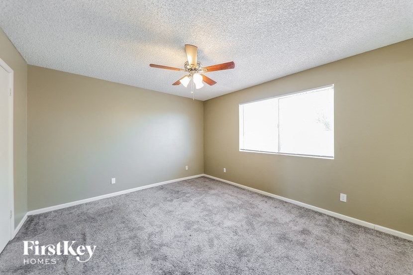 an empty living room with a ceiling fan and a window
