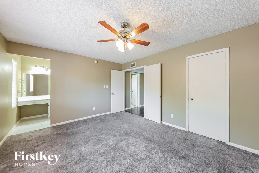 a spacious living room with carpet and a ceiling fan