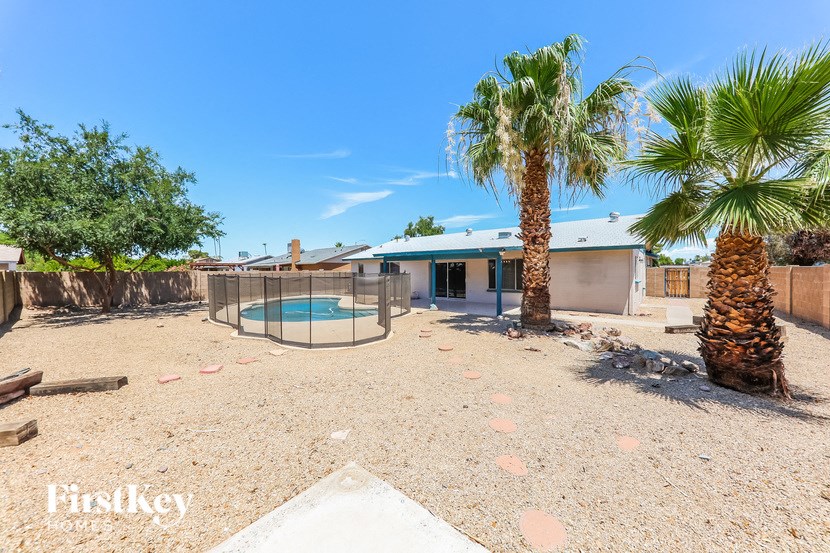 a house with a yard with a pool and palm trees