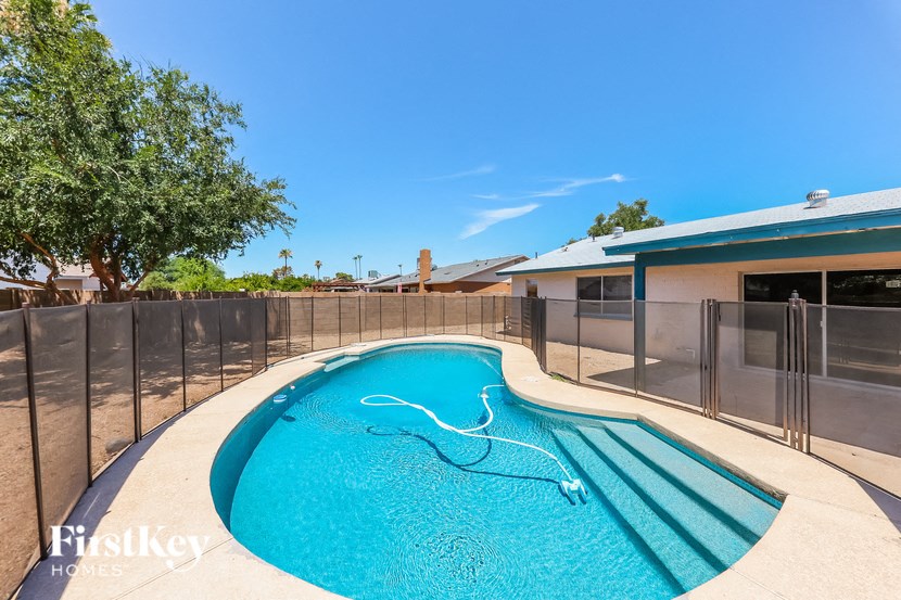 a large pool in a backyard with a fence and a house