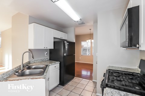 A kitchen with a sink, refrigerator, and a stove top oven.