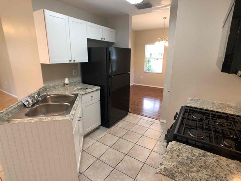 A kitchen with a black refrigerator, sink, and stove.