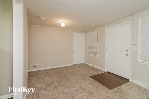 a spacious living room with carpet and a white door