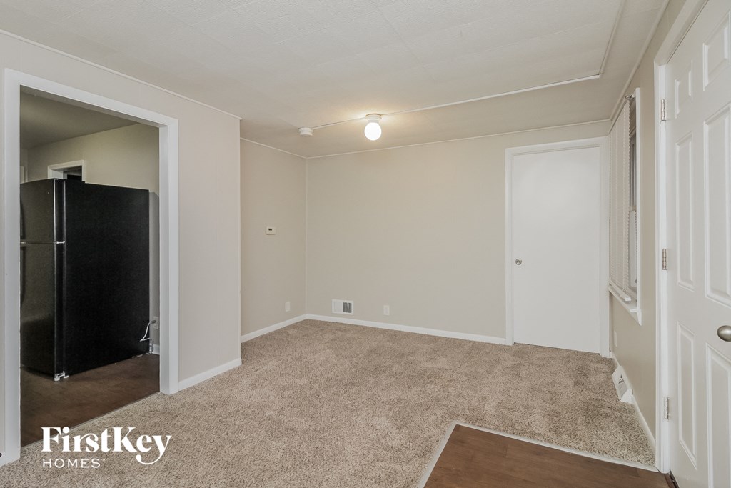 an empty living room with a closet and a black refrigerator