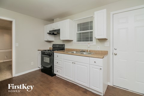 a kitchen with white cabinets and a sink and a stove