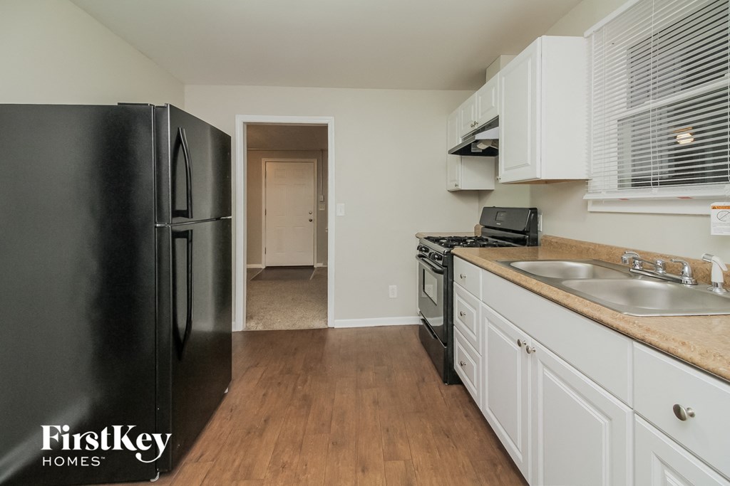 a kitchen with white cabinets and a black refrigerator