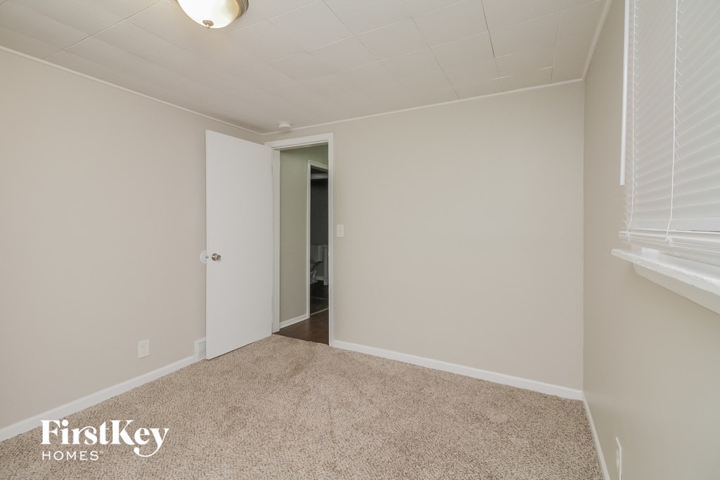 a bedroom with a carpeted floor and a door to a bathroom