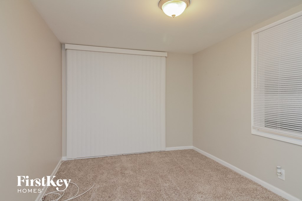 a bedroom with a closet and a window with a white roller closet door